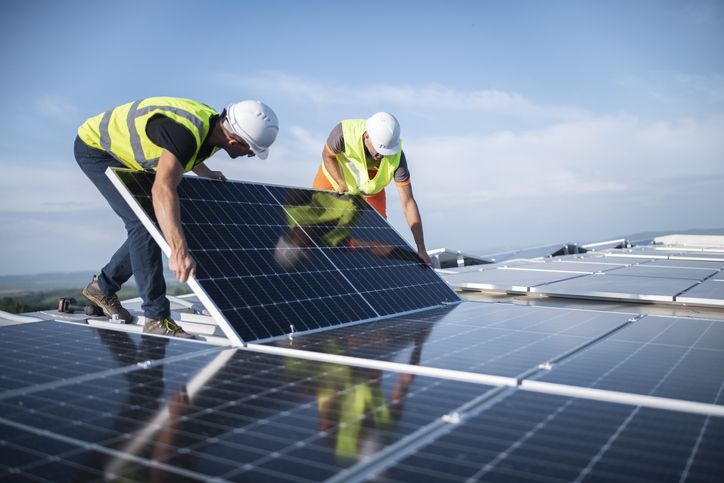 Two engineers installing solar panels on roof.